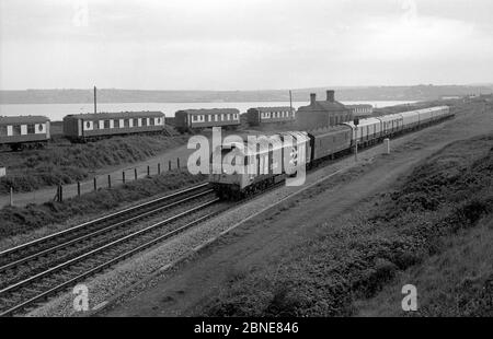 Diesellokomotive der Baureihe 50 Nr. 50046 „Ajax“, die einen Royal Mail-Zug an den ehemaligen Pullman-Ferienwagen in Marazion, Cornwall, England, vorbeizieht. 1987. Stockfoto