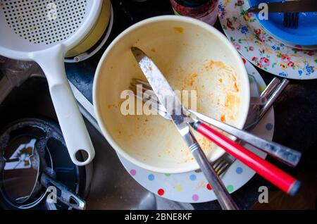 Abwaschen - Teller, Geschirr, Messer, Gabeln, Tassen auf einer Küchenarbeitsplatte gestapelt, die bereit ist, gereinigt zu werden. Stockfoto