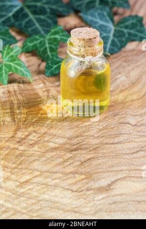 Eine Flasche Pflanzenöl auf einem schönen strukturierten Holztisch. Omega-3-essentielle mehrfach ungesättigte Fettsäuren. Leinsamenöl in einer Flasche. Grüne Blätter Stockfoto