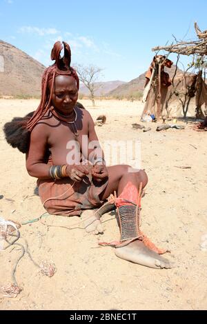 Himba Frau Anpassung ihrer traditionellen "Omohanga" Fuß Ornament, ein 21 Strang geschichteten Fußkettchen, zeigt an, ob sie verheiratet ist und Kinder hat, Marienfluss Stockfoto