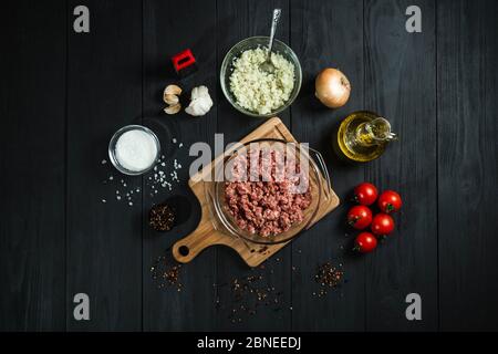 Rohes Hackfleisch mit Zutaten auf schwarzen Holzbrettern. Blick von oben. Stockfoto