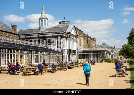 Leute, die draußen im Pavilion Gardens Buxton an einem sonnigen Tag essen und trinken Stockfoto