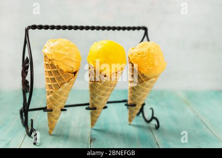 Drei gelbe Eiszapfen, die in einem Stand auf einem Vintage-Tisch bleiben Stockfoto
