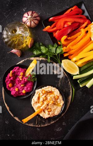 Draufsicht auf eine Platte mit frischem Gemüse und verschiedenen Hummus Dips Stockfoto