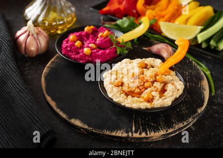 Nahaufnahme von verschiedenen veganen Hummus Dips mit gesundem Gemüse Stockfoto