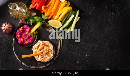 Bunt und bunt sortierte frische Gemüseplatte mit verschiedenen Hummus Dips Stockfoto