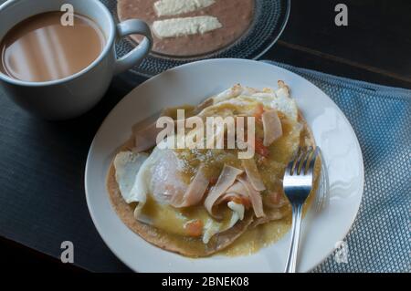 Seitenansicht von huevos Rancheros oder Ranch Eier mit gebratenen Bohnen, Ziegenkäse und Milchkaffee, mexikanisches Frühstück Konzept Stockfoto