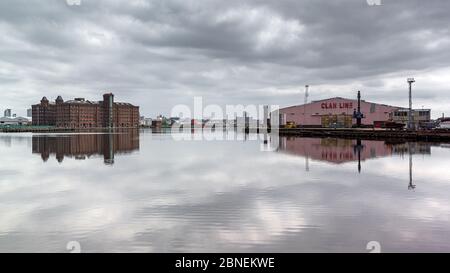 East Float Dock Becken, Birkenhead. Spiegelte East Float Quay und Clan Line Schuppen Gebäude und Himmel. Stockfoto