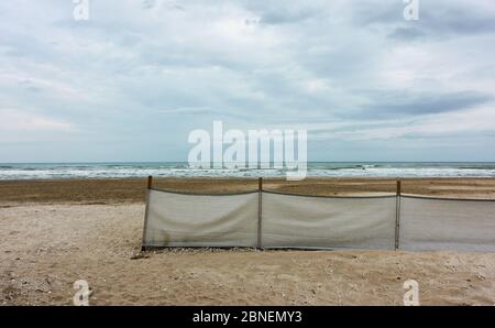 Sandstrand mit Stoffzaun in Rimini in der Nebensaison, Italien. Landschaft - Meereslandschaft Stockfoto