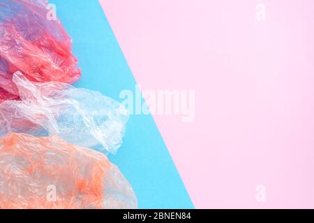 Zerknitterte Plastiktüten auf blauem und rosa Hintergrund mit Kopierspase. Müllsortierung und Erhaltung Ökologie Konzept. Flatlay-Komposition. Stockfoto