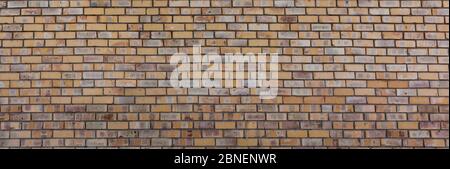 Alte Ziegelmauer von gelber Farbe, breites Panorama des Mauerwerks. Stockfoto
