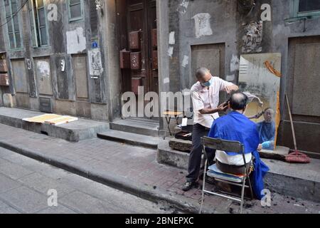 KANTON, CHINA – CA. MAI 2020: Ein Straßenbarbier arbeitet täglich in der Gasse der Altstadt von Guangzhou. Stockfoto