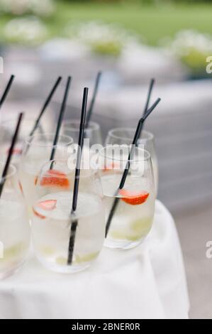 Eiskalte Holunderblüten-Cocktail-Drinks mit schwarzen Strohhalmen auf weißem Tischtuch Stockfoto