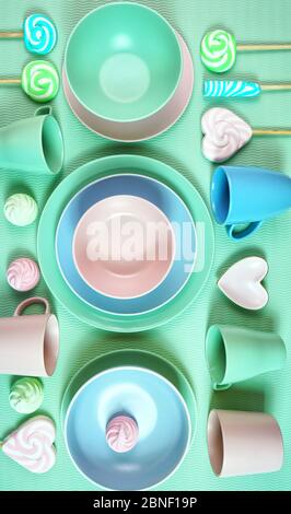 Draufsicht auf modernes, in Pastellrosa, grün und blau gedeckter Keramikgeschirr in hellgrün. Kreatives Konzept Kochen, Küche flat Layout vertikal orientiertat Stockfoto