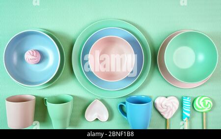Draufsicht auf modernes, in Pastellrosa, grün und blau gedeckter Keramikgeschirr in hellgrün. Kreatives Konzept Kochen, Küche Flatlay Layout mit negativen Cop Stockfoto