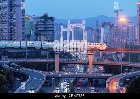 --FILE--EIN Zug bewegt sich auf der Eisenbahn mit Wahrzeichen und Wolkenkratzern als Hintergrund, Chongqing, China, 17. August 2018. Zhou Zhiyong, ein Fotograf wh Stockfoto