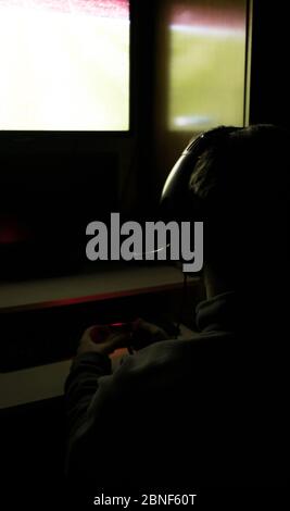 Rückansicht eines Mannes, der Videospiele in seinem spielt Schlafzimmer mit dem l Stockfoto