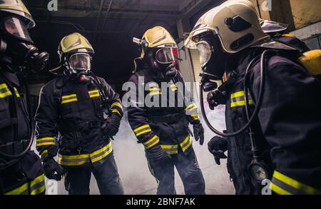 Gruppe von Feuerwehrleuten in der Feuerwehr, die ihre Gasmaskenausrüstung überprüfen Stockfoto
