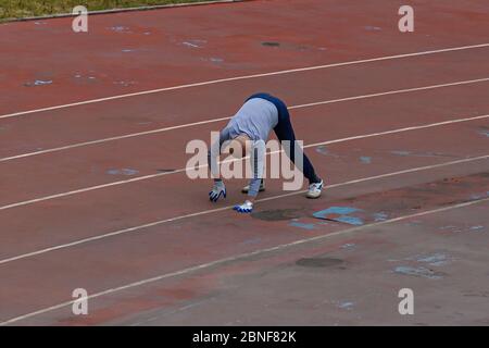 Ein alter Mann wird durch Nachahmung Schildkröten und Schlangen zu kriechen, um alle Gelenke im Körper zu verbessern und die Gesundheit auf einem Spielplatz zu verbessern gesehen, Stockfoto