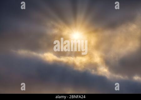 Ein Sonneneinbruch bricht durch die leuchtenden, hellen, detaillierten Wolken Stockfoto