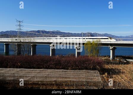 Ein Blick auf einen Zug von Fuxing Hao, auch bekannt als die CR-Serie EMU, läuft auf der Guanting Reservoir Brücke von Beijing-Hohhot Railway, Huailai County, Stockfoto
