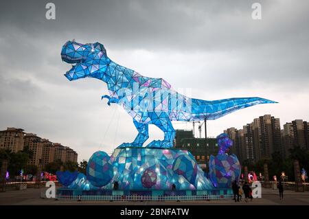 Ein riesiges Dinosaurierlicht erscheint auf einem Platz und fällt den vorbeiziehenden Bürgern der Stadt Changzhou, der Provinz Jiangsu in Ostchina, am 19. April 2020 auf. Stockfoto
