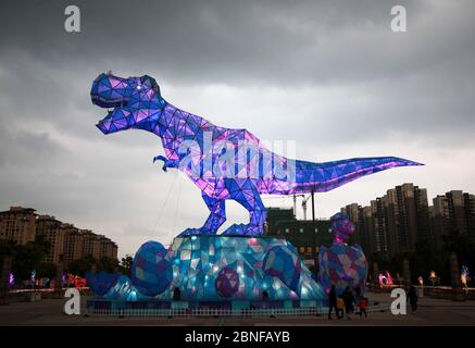 Ein riesiges Dinosaurierlicht erscheint auf einem Platz und fällt den vorbeiziehenden Bürgern der Stadt Changzhou, der Provinz Jiangsu in Ostchina, am 19. April 2020 auf. Stockfoto