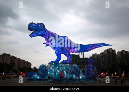 Ein riesiges Dinosaurierlicht erscheint auf einem Platz und fällt den vorbeiziehenden Bürgern der Stadt Changzhou, der Provinz Jiangsu in Ostchina, am 19. April 2020 auf. Stockfoto