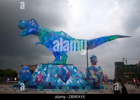 Ein riesiges Dinosaurierlicht erscheint auf einem Platz und fällt den vorbeiziehenden Bürgern der Stadt Changzhou, der Provinz Jiangsu in Ostchina, am 19. April 2020 auf. Stockfoto