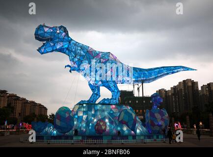 Ein riesiges Dinosaurierlicht erscheint auf einem Platz und fällt den vorbeiziehenden Bürgern der Stadt Changzhou, der Provinz Jiangsu in Ostchina, am 19. April 2020 auf. Stockfoto
