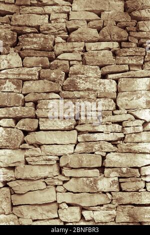 Vertikale Graustufen Aufnahme einer alten Wand mit uneben gemacht Größe der Steine Stockfoto