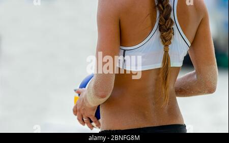 Eine weibliche Beach Volleyball Spieler ist immer bereit, den Ball zu dienen Stockfoto