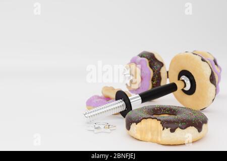 Hantel oder Langhantel in Form eines Donuts auf weißem Hintergrund. Erdbeer- und Schokoladenaromen und mit Streuseln auf Donut. Konzept des sterben Stockfoto