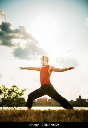 Junger Mann, der Yoga im Park macht Stockfoto