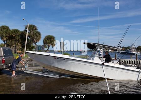 Zwei Männer holen ihr Fischerboot von Manatee Pocket auf der Sandsprit Park Bootsrampe in Port Salerno, Florida, USA. Stockfoto