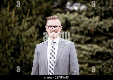 Schöner Mann im Anzug im Freien mit verschwommenem Grün in Der Hintergrund Stockfoto