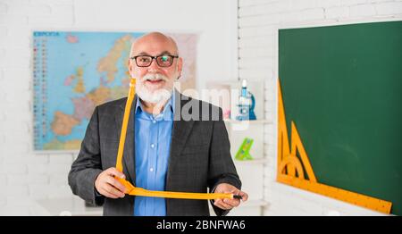 Konzept der mathematischen grafischen Werkzeuge. In Richtung Wissen. Studieren Sie Mathematik, um gute Ergebnisse zu erhalten. Senior Mann Lehrer verwenden Kompass-Tool. Bärtige Tutor Mann zeichnen mit Kompass auf Tafel. Zurück zur Schule. Stockfoto