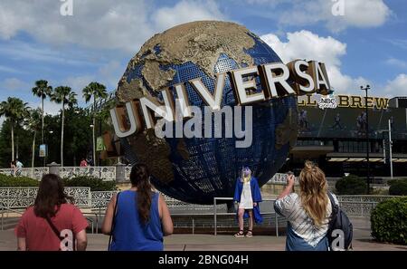 Orlando, Usa. Mai 2020. Ein Absolvent, der eine Mütze, ein Kleid und eine Gesichtsmaske trägt, posiert für ein Foto auf dem Universal Orlando's CityWalk, als Teile des Unterhaltungs- und Einkaufsviertels heute zum ersten Mal seit der Schließung von Universal Orlando am 15. März für begrenzte Stunden eröffnet wurden. 2020 aufgrund der Coronavirus-Pandemie.Neben Gesichtsbezügen sind auch Temperaturkontrollen erforderlich. Die Freizeitparks von Universal sind bis mindestens Mai 31 geschlossen. Quelle: SOPA Images Limited/Alamy Live News Stockfoto