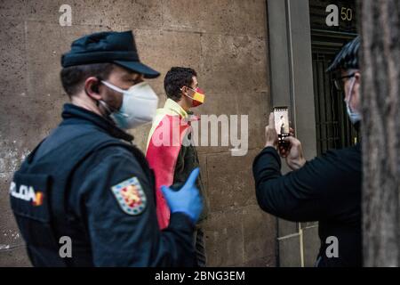 Ein Polizist warnt einen Mann, der während der Demonstration auf der Straße Fotos von Demonstranten macht, die in eine spanische Flagge gehüllt sind. Die Bewohner des gehobenen Viertels Salamanca protestieren gegen die Regierungsführung der Coronavirus-Krise. Einige Teile Spaniens haben seit ihrer Coronavirus-Blockade den Übergang in die Phase 1 aufgenommen, so dass viele Geschäfte und Restaurants, die Outdoor-Kunden bedienen, wieder geöffnet werden können. Die am stärksten von der Covid-19 betroffenen Orte wie Madrid und Barcelona befinden sich jedoch weiterhin in einer strengeren Phase-0-Quarantäne. Stockfoto