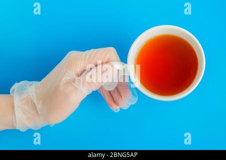 Doctor Hand in medizinischen Handschuh hält die weiße Tee-Tasse von oben Stockfoto