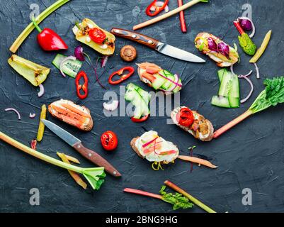 Leckere italienische Bruschetta mit Gemüse und Zutaten auf dem Küchentisch Stockfoto