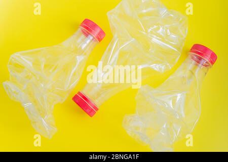 Drei zerquetschte Plastikflaschen lagen flach auf dem gelben Hintergrund. Kein Abfall- und Recyclingkonzept Stockfoto