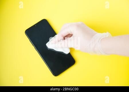 Hand In Schutzhandschuh Mit Serviettenreinigungs-Mobiltelefon. Coronavirus Desinfektion Konzept. Stockfoto