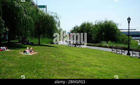 Menschenmenge, die sich auf dem Stadtpark unter dem Rasen entspannen Ein blauer, sonniger Himmel Stockfoto