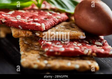 Rote Bete und Roggenmehl Cracker mit Gemüse für Snacks auf schwarzem Hintergrund. Vegetarismus und gesunde Ernährung Stockfoto