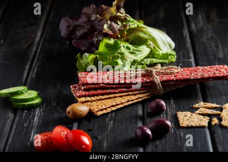 Rote Bete und Roggenmehl Cracker mit Gemüse für Snacks auf schwarzem Hintergrund. Vegetarismus und gesunde Ernährung Stockfoto