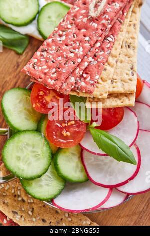 Rote Bete und Roggenmehl Cracker mit Gemüse für Snacks auf einem hölzernen Hintergrund. Vegetarismus und gesunde Ernährung Stockfoto