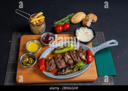 Hausgemachte Fleischbällchen mit geröstetem Rindfleisch in gusseiserner Pfanne auf Holztisch in der Küche, frische Petersilie, Vintage-Gabel Stockfoto