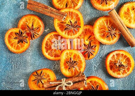 Scheiben getrockneter Orangen oder Mandarinen mit Anis und Zimt, auf blauem Hintergrund. Vegetarismus und gesunde Ernährung Stockfoto