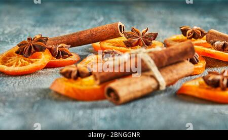 Scheiben getrockneter Orangen oder Mandarinen mit Anis und Zimt, auf blauem Hintergrund. Vegetarismus und gesunde Ernährung. Stockfoto